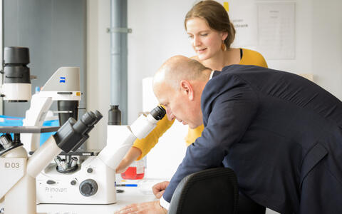 The governing mayor Kai Wegner looks into a microscope