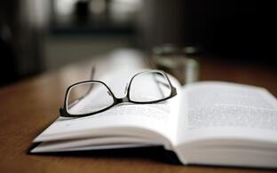 Eine Brille liegt auf einem aufgeschlagenen Buch