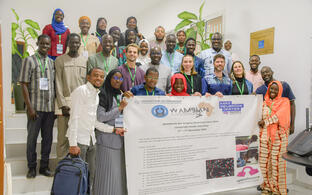 Group photo of participants at the WAMBIAN Bio-Imaging Workshop holding a banner with event details.