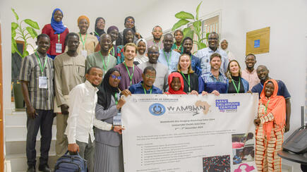 Group photo of participants at the WAMBIAN Bio-Imaging Workshop holding a banner with event details.